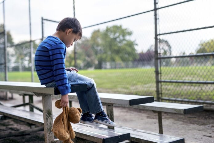 Young boy looking depressed and alone on the bleachers