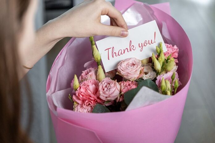 Hand,Holding,A,Thank,You,Card,In,A,Bouquet,Of